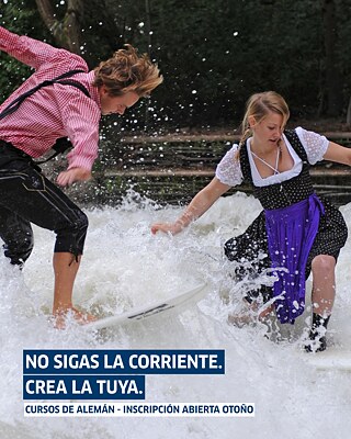 Ein Mann und eine Frau jeweils in bayrischer Tracht auf einem Surfbrett reiten auf künstlichen Wellen in München