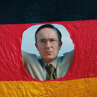 A man looks through a hole cut out of a German flag.