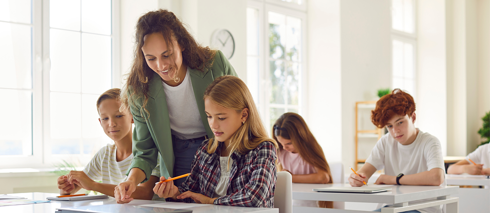 Lehrerin unterstützt Schüler im Unterricht in Gruppen