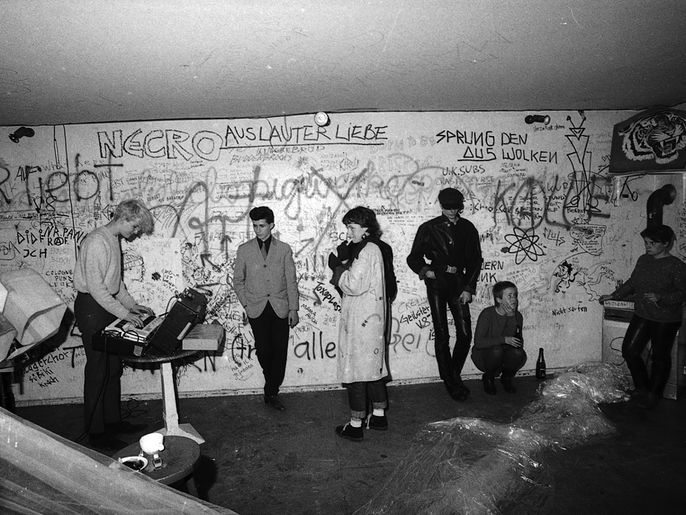 Alex Hacke (a.k.a. Alexander von Borsig, left) playing with Kiddy Citny (Sprung aus den Wolken) to a small audience: Silvie Langenfeld (3rd from left), Blixa Bargeld (Einstürzende Neubauten, 4th from left), Risiko, Westberlin, 1981. 