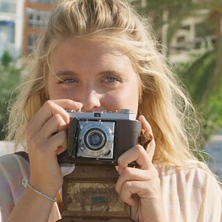 Eine Figur des Films hält einen Moment der Reise mit einer analogen Kamera fest.