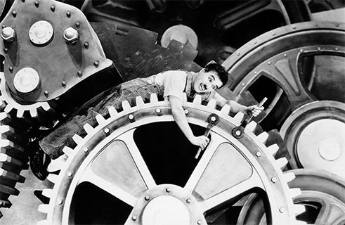 <b>“Modern Times” by Charlie Chaplin (1936)</b><br>Charlie Chaplin’s childhood was marked by bitter poverty. In his slapstick comedies, the US director and actor always took up the causes of the poor and disenfranchised, pointing out the social injustices caused by capitalist modes of production. <i>Modern Times</i> from 1936 portrays the hardscrabble life of Chaplin’s famous tramp figure following the Great Depression of 1929, years shaped by mass unemployment and Fordist capitalism. There has never been a more playful and entertaining depiction of Marx’s concept of “estranged labour” than the famous factory scene in which the tramp falls onto a conveyor belt and is pulled into the cogs of a giant machine.