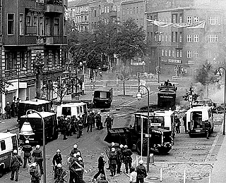 In 1981, squats were cleared in Berlin with a large police tone. In the context of this event, 18-year-old Klaus-Jürgen Rattay was killed by unclear circumstances. The next night there was serious violence between the police on the one hand and the squatters and their sympathizers on the other.