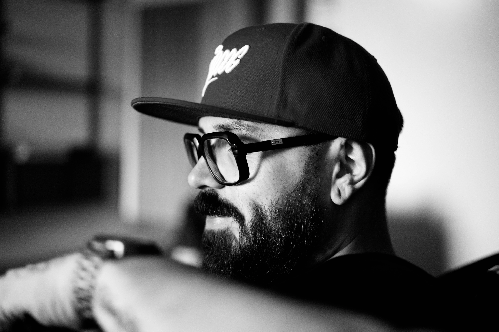 Schwarz-weiß Foto des Graffitikünstlers Hombre SUK, Ansicht in Profil, Homre trägt Bart und Brille