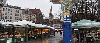 <b>Viktualienmarkt (Munich, Allemagne)</b><br><br>Tôt le matin, le Viktualienmarkt, situé en plein cœur de Munich, est encore vide. Mais pendant la journée, du lundi au samedi, les touristes et les locaux s’y pressent pour acheter des fruits, des légumes, des sandwichs au saucisson, des spécialités locales, des jus de fruits ou des fleurs. Les plus aisés, le « gratin » de Munich, y boivent leur vin blanc – le Viktualienmarkt est en effet considéré comme un marché relativement cher. Même si tous les habitants de Munich n'y font pas leurs emplettes, ce marché est connu dans toute l'Allemagne : il a déjà servi de décor pour un épisode de la plus célèbre des séries criminelles allemandes, Tatort, et figure même sur un timbre.