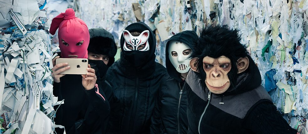 Image fixe de la série Netflix "We Are The Wave" (Nous sommes la vague)  - Cinq personnes masquées se cachant entre des balles de papier recyclé