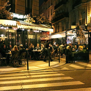 Une scène familière chaque nuit dans les rues de Paris : malgré le froid hivernal, les gens restent assis à l’extérieur des bars jusque tard dans la nuit. Sous les radiateurs et à l’abri du vent et de la pluie, les gens y boivent, fument et rient. C’est un art de vivre qui peut sembler étrange au premier regard et surtout en hiver ; mais une fois qu’on l’a soi-même essayé, on comprend pourquoi les gens y prennent du plaisir, enveloppés dans une couverture et pouvant observer l’agitation de la ville. Une nuit typique à Paris, c’est une nuit entre amis devant un bar ou un café.