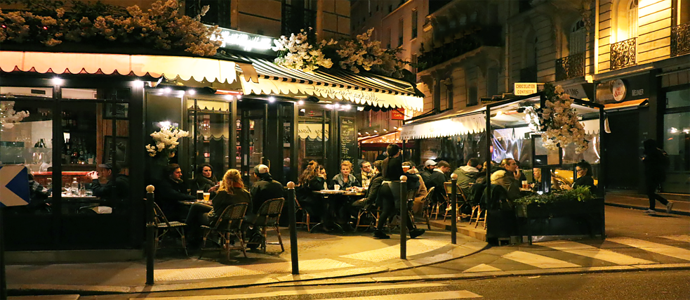 Eine bekannte Szene jede Nacht in den Straßen von Paris: Trotz winterlicher Kälte sitzen die Leute bis tief in die Nacht draußen vor den Bars. Unter Heizstrahlern und vor Wind und Regen geschützt wird hier getrunken, geraucht und gelacht. Es ist ein Lebensgefühl, welches auf den ersten Blick und vor allem im Winter komisch wirken kann; aber probiert man es einmal aus, versteht man, warum es -eingewickelt in eine Decke und mit Blick auf das rege Treiben der Stadt - zu einem Genuss wird. Eine typische Nacht in Paris bedeutet also eine Nacht mit Freunden vor einer Bar oder einem Café. 