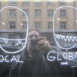  Dan Perjovschi macht in einem spiegelnden Fenster ein Selfie; auf dem Fenster sind links und rechts Köpfe skizziert mit den Unterschriften local und global ©  © Dan Perjovschi Dan Perjovschi
