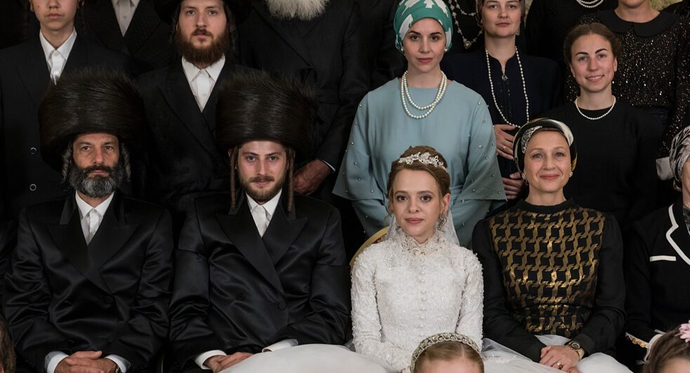Nada ortodoxa: Yanky (Amit Rahav) e Etsy (Shira Haas) com suas famílias em uma foto de casamento.