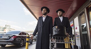 Unorthodox still image: Yanki (Amit Rahav) and Moishe (Jeff Wilbusch) arrive at the Berlin Airport in search of Esty.