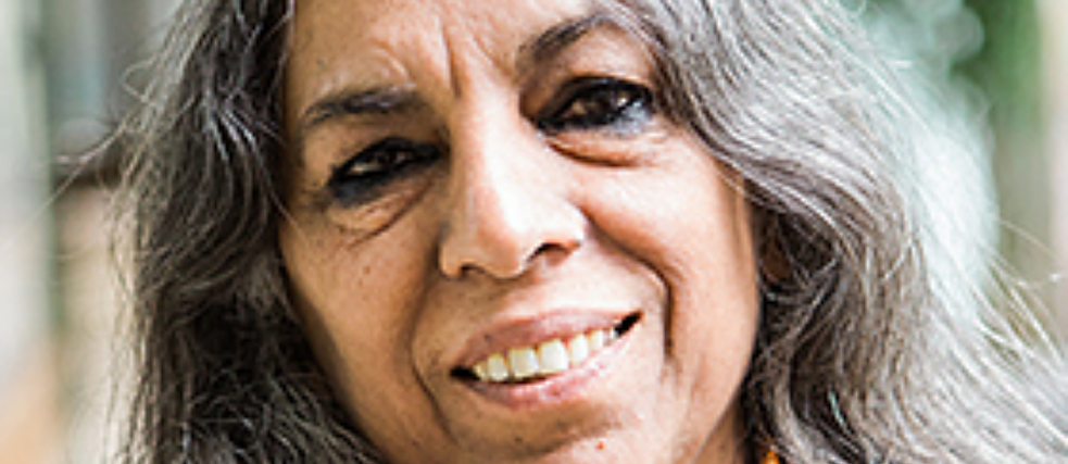Portrait of Urvashi Butalia;  she has long gray-black hair and smiles into the camera