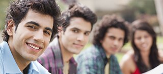 Bewerbung der Sprachkurse und Prüfungen in der Region SAS – Mehrere junge Studenten sitzen nebeneinander im Park