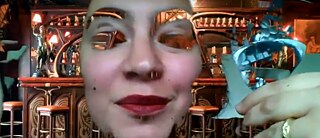A woman wearing lipstick holding a cocktail appears in front of a bar, with parts of her face disappearing due to a camera glitch.