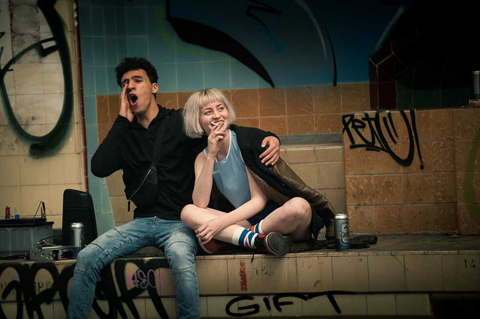 Standbild aus der Netflix Germany original series "We are the wave"  Rahim (Mohamed Issa) und Paula (Sarah Mahita) kommen sich in der verlassenen Fabrik näher.