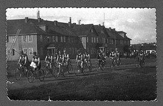 Teilnehmer*innen der Radtour Kemerowo-Anschero-Sudschensk vor dem hölzernen Kommunehaus für 250 Bewohner*innen, gebaut 1922. Kemerowo // 1922